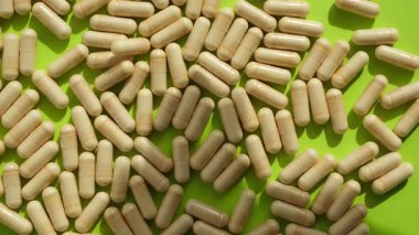 Biyolojik olarak aktif katkı maddelerinin arka planında belirsiz el gölgesi hareketi. Rutinimize takviye eklemeyi düşünüyorum. Sarı-yeşil arka plan, güneş gölgeleri.