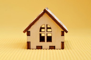 Ahşap Oyuncak ev modeli üzerinde sarı arka plan, önden görünüm