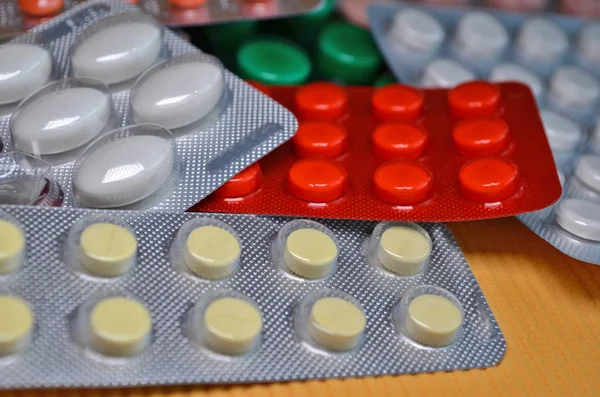 White, red, green round and oval medical tablets in pack, tablets packed in blisters closeup