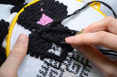Kadın el nakışı ile siyah ve pembe yün iplik, sarı çember, closeup beyaz kumaş üzerine embroiders