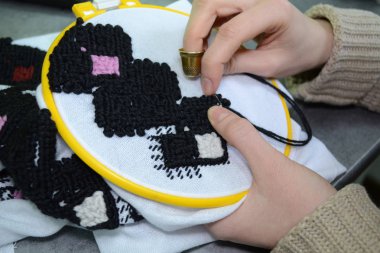Kadın el ile görünümü closeup yaptı hoop, siyah ve pembe yün iplik beyaz kumaş üzerine Ukrayna nakış tarafından embroiders