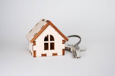 Wooden house with key on gray background, concept for selling houses, with copyspace clipart