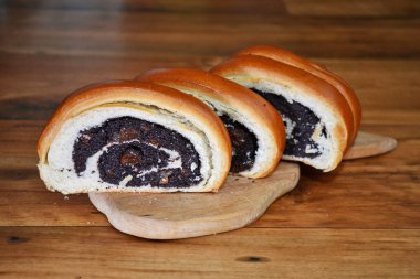 Ahşap yüzey üzerinde ahşap kesme tahtası üzerinde haşhaş tohumu ile dilimlenmiş kırmızı taze topuz yatıyor