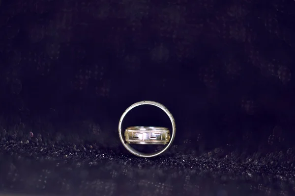Two silver vintage wedding rings on a dark blue shiny surface, with a blurred background and space for text