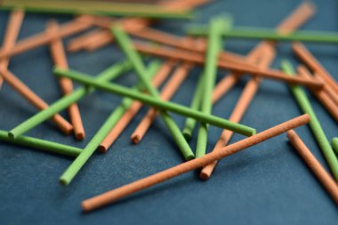 Yeşil ve turuncu Hint tütsü sopa koyu gri arka plan üzerinde geometrik kompozisyon karıştırılır