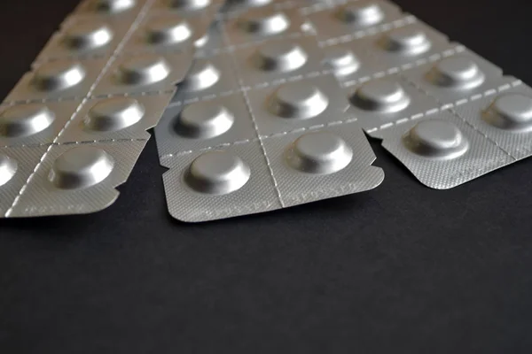 Round medical tablets in three packs, tablets packed in the blisters on the top, with copyspace on black background