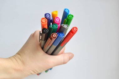 Beyaz arka plan üzerinde kadının elinde tutan kalemler dizi gökkuşağı renkli