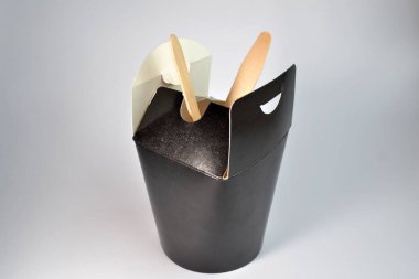 Tek kullanımlık siyah kare karton paket servisi olan restoran gıda açın konteyner içlerinde beyaz zemin üzerine tahta kaşık ve çatal