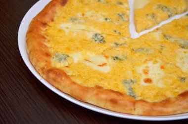 Koyu ahşap masa üzerinde beyaz bir plaka dört peynirler ile pizza, çekim