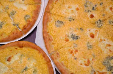 Karanlık bir arka planda farklı boyutta peynir dört çeşit ile üç pizza