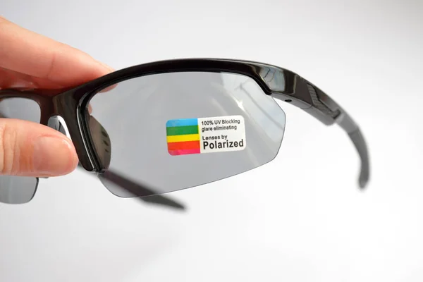 De zwarte zonnebril van de sport met fotochrome en het polariseren effect met sticker, die in hand op witte achtergrond houdt — Stockfoto