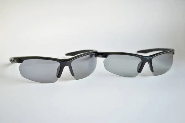 Two sport black sunglasses with photochromic and polarizing effect on white background — Stock Photo, Image