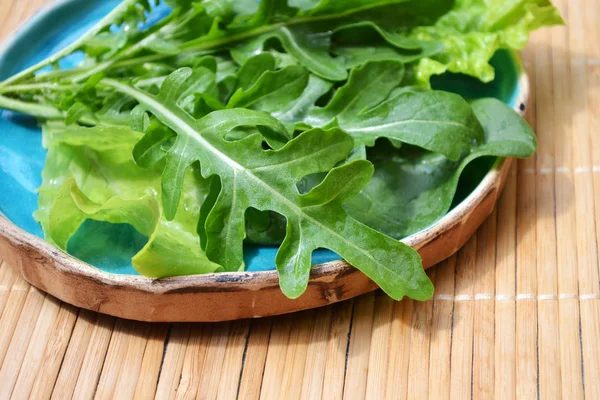 Летняя смесь овощей салат из рукколы шпината в голубой тарелке на деревянной поверхности — стоковое фото