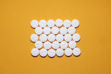 Görünümü çok sayıda beyaz düzgün dışbükey tabletler sarı çizgili arka planda, dikdörtgen biçimli, bölen şeridi ile top