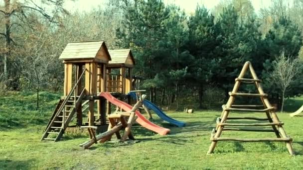 Kinderspielplatz im Sommer mit Schaukeln und Rutschen aus Holzbalken — Stockvideo