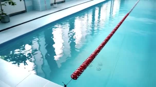 Moderní krytý bazén s modrou vodou a zdmi, pohled na plavecké stezky — Stock video