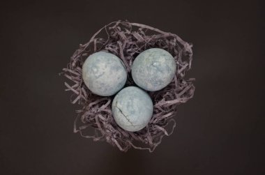 Üç mavi yumurta, çay ebegümeci boyalı, siyah arka plan üzerinde bir yuvada yalan, ejderha yumurta ve mermer gibi, üst görünümü