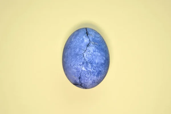 Синее яйцо с трещиной, окрашенное в чай гибискус, на желтом фоне, похожее на планету и мрамор с копирайтом — стоковое фото