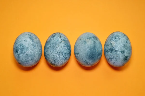 Vier blaue Eier, bemalt mit Tee-Hibiskus, auf orangefarbenem Hintergrund, ähnlich wie Planeten und Marmor mit Kopierraum — Stockfoto
