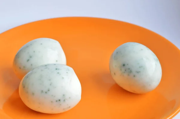 Три очищені яйця після фарбування в чаї з гібіскусом, виглядають як зіпсовані та покриті цвіллю на помаранчевій тарілці — стокове фото
