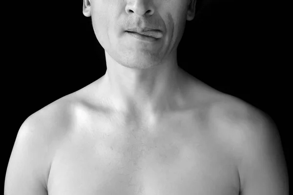 男人裸露的胸部和黑色背景的一半脸。一个男人开玩笑地展示他的舌头。黑白照片 — 图库照片