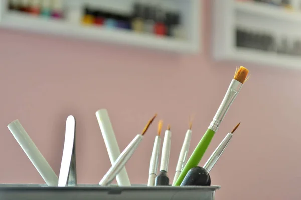 Brushes and tools for manicure and nail art in the beauty salon on the background of a shelves with nail polish