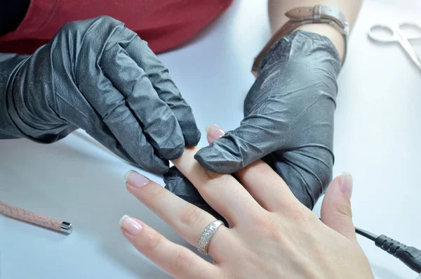 Manicura en guantes negros frota uñas barnizadas —  Fotos de Stock