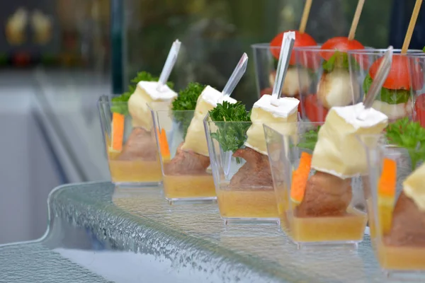 Diferentes encontram canapés em copos transparentes e espetos de madeira em um suporte de passo de vidro em um banquete — Fotografia de Stock