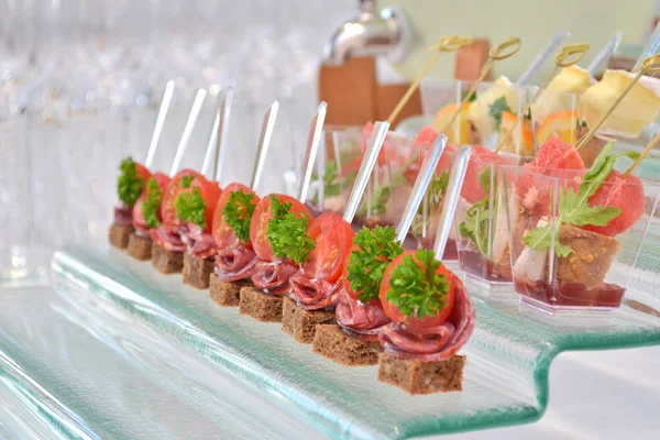 Deux types de canapés avec des brochettes transparentes et en bois sur un support de marche en verre sur un banquet — Photo