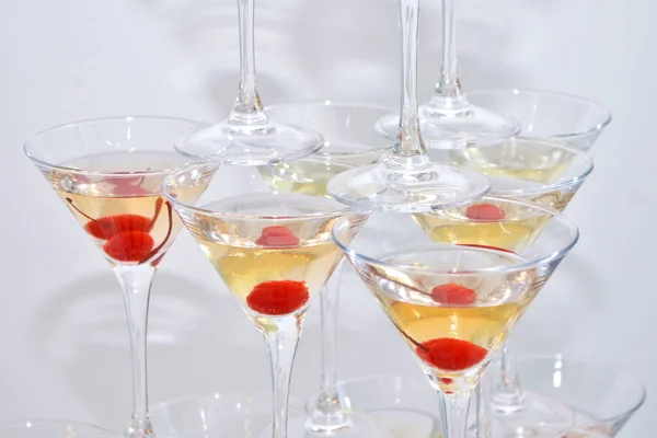 Triangular martini glasses, filled with champagne with cherries built in the shape of a pyramid, top view