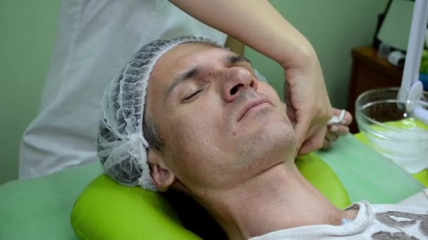 En kosmetolog gnuggar man hud med bomull pad med rengöringsmedel innan förfarandet — Stockvideo