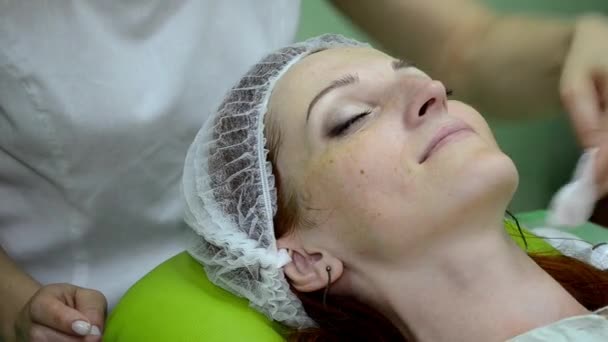 Косметолог натирає шкіру білої дівчини ватним майданчиком після косметичного прибирання — стокове відео