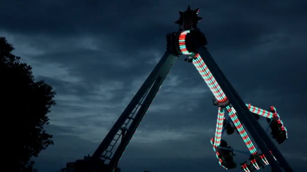Extrémní atrakce v zábavním parku s měnícím se světlem, v temné práci — Stock video