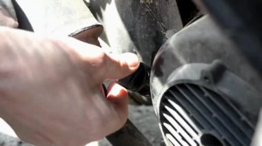 Bir motosiklette motor yağı seviyesini kontrol eden bir adam vanayı söküyor