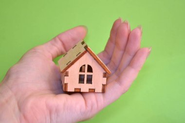 Kız el açık palmiye ahşap minyatür oyuncak evde yeşil arka plan ile tutarak, copyspace ile