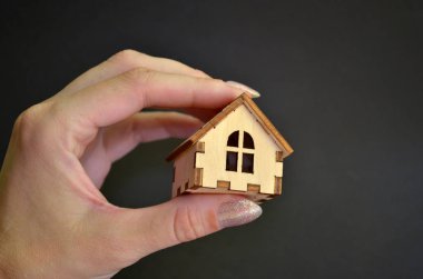 Siyah arka plan ile bir ışık üzerinde ahşap ev tutan kız el, copyspace ile