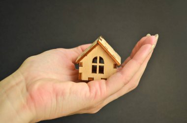 Siyah arka plan ile ışık açık palmiye ahşap minyatür oyuncak evde kız el tutan, copyspace ile