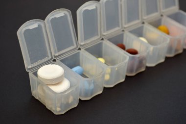 Haplar için Plastik günlük organizatör, bir copyspace ile siyah arka plan üzerinde farklı hapları ile kutu, yan görünüm