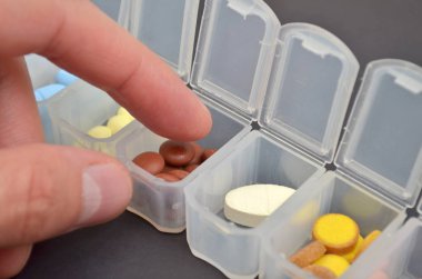Adam el copyspace ile siyah bir arka plan üzerinde haplar için plastik organizatör kahverengi hapları almak istiyorum