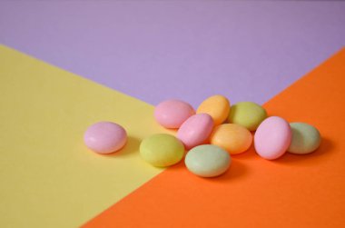 Yuvarlak renkli şekerler üç renkli üçgenler, geometrik arka plan üzerinde yığın yalan