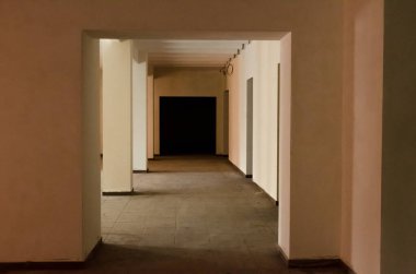 Pencerelerden gelen ışık altında direkleri ve koridorları olan monolitik bir binanın boş alanı.