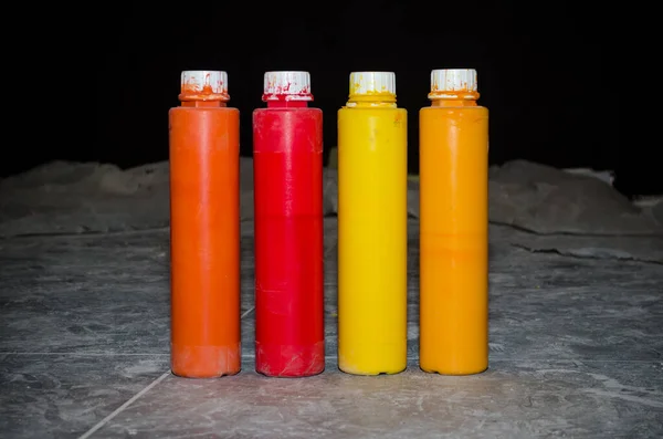 四个装有油漆、秋天色彩、红色、黄色、橙色的长瓶子，在修理过程中被放置在肮脏的地板上 — 图库照片