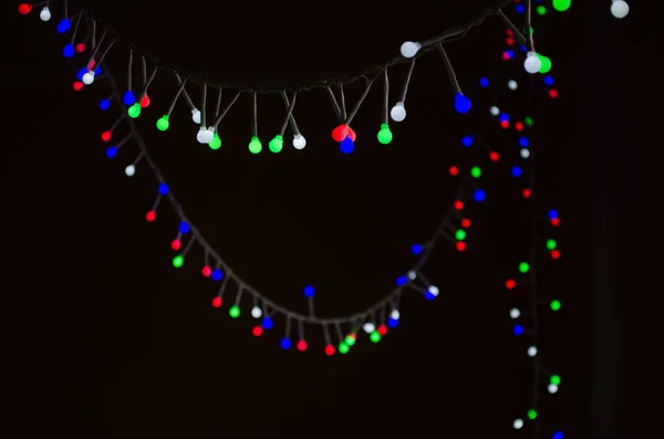 Fondo de Navidad con brillantes luces de guirnalda de colores sobre fondo negro. Postal de Año Nuevo — Foto de Stock