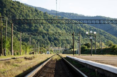 Demiryolu rayları ve istasyon platformu yüksek Karpatya dağlarının arka planına karşı