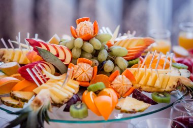 Şenlik tablo. Karışık meyve. Elma, muz, greyfurt, mandalina, ananas, kivi küçük parçalar halinde doğranmış.