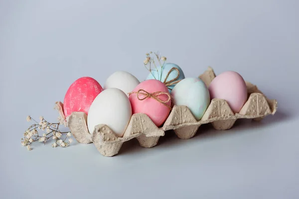 Tray with white and pink eggs on a gray background. Easter decor.