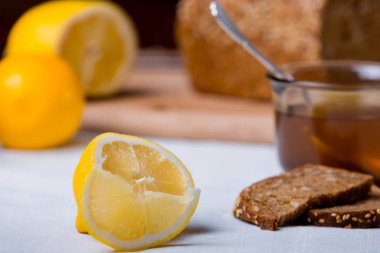Çay ile limon doğranmış dilimleri. Narenciye ekmek ile çay yanında masada.
