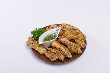 Tavada kavrulmuş balık parçalarhalinde kesilir ve sarımsak sosu ve otlar ile beyaz bir tabak üzerine serilir. Beyaz arka planda lezzetli yemekler.