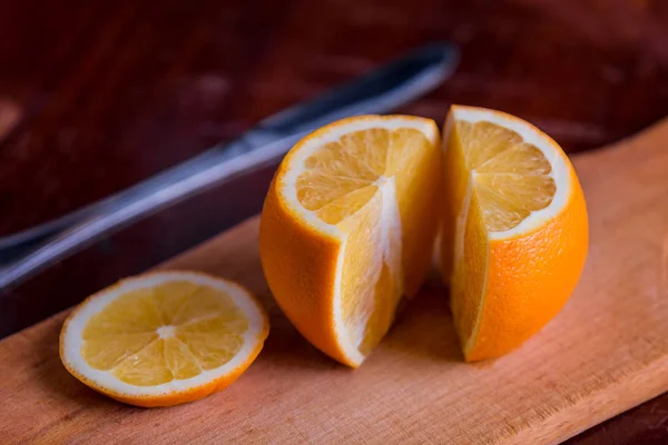 Juicy orange. Sliced orange for two. Slicing orange on pieces of fruit salad. On a wooden board.
