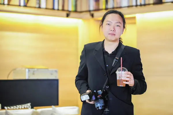 轻松的亚洲摄影师手持饮料和照相机 — 图库照片